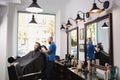 The man barber serves the client in the salon