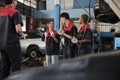 Group of mechanic workers is cheerful with finished repair work at car garage.