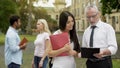 Male professor discussing thesis with asian female student near university Royalty Free Stock Photo