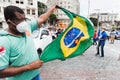 Male Protester with face mask holding the Brazilian flag during a demonstration against Bolsonaro