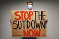 Male protester holding placard against coronavirus lockdowns against grey background Royalty Free Stock Photo