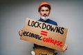 Male protester holding placard against coronavirus lockdowns against grey background Royalty Free Stock Photo