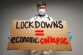 Male protester holding placard against coronavirus lockdowns against grey background Royalty Free Stock Photo