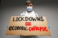 Male protester holding placard against coronavirus lockdowns against grey background Royalty Free Stock Photo