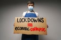 Male protester holding placard against coronavirus lockdowns against grey background Royalty Free Stock Photo