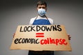 Male protester holding placard against coronavirus lockdowns against grey background Royalty Free Stock Photo