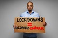 Male protester holding placard against coronavirus lockdowns against grey background Royalty Free Stock Photo