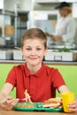 Male Pupil Sitting At Table In School Cafeteria Eating Unhealthy Royalty Free Stock Photo