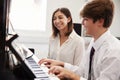 Male Pupil With Teacher Playing Piano In Music Lesson