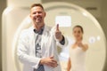 Male radiologist and female patient showing thumbs up near CT scanner in hospital. Royalty Free Stock Photo