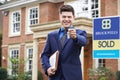 Male Realtor Standing Outside Residential Property Holding Keys