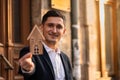 Male realtor standing outside residential property holding wood house Royalty Free Stock Photo