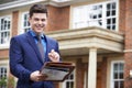 Male Realtor Standing Outside Residential Property