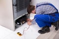 Male Repairman Checking Fridge With Digital Multimeter Royalty Free Stock Photo