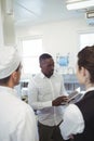 Male restaurant manager using digital tablet while briefing to his kitchen staff Royalty Free Stock Photo