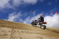 Male riding ATV up sand dune hill Royalty Free Stock Photo