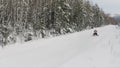 Male riding snowmobile, moving fast towards camera. Clip. Aerial view of a winter snow covered pine forest and empty Royalty Free Stock Photo