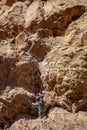 Male rock climber attached to rope climbs desert rock wall