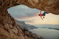 Male rock climber climbing along a roof in cave at sunset Royalty Free Stock Photo