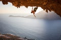 Male rock climber climbing along a roof in a cave