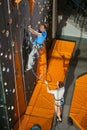 Male rock-climber practicing climbing on rock wall indoors