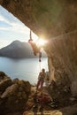 Male rock climber starting challenging route on cliff at sunset, female climber belaying him Royalty Free Stock Photo