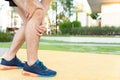 Male runner athlete leg injury and pain. Hands grab painful knee while running in the park Royalty Free Stock Photo