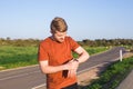 Male runner jogging outside looking at his wearable fitness tracker outside.