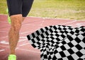 Male runner legs on start line with checkered flag