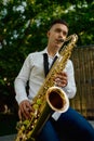 Male saxophonist plays the saxophone in park