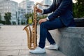 Male saxophonist with sax, buildings on background Royalty Free Stock Photo