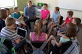 male school teacher sitting on a chair in a circle with a group of schoolchildren Royalty Free Stock Photo