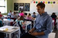 Male school teacher sitting on a desk in an elementary school classroom Royalty Free Stock Photo