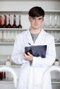 A male science student writing on a clipboard