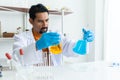 Male science teacher in a white coat sits in the science room looking serious about finding the results of experiments to teach Royalty Free Stock Photo