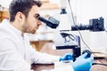 Male scientist, chemist working with microscope in pharmaceutical laboratory, examinating samples Royalty Free Stock Photo