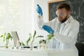 male scientist conducts experience in laboratory working with laptop computer, plant growing in lab. Researcher holding Royalty Free Stock Photo