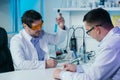 Male scientist in lab working in pharmaceutical studies and medical research with microscope and liquids in test tubes. Royalty Free Stock Photo