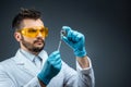 Male scientist, laboratory assistant in a white coat and glasses holds a bottle with a vaccine in his hands, medical tests, Royalty Free Stock Photo