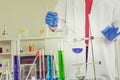 Male scientist performs an experiment on chemical test tube in a laboratory wearing blue gloves