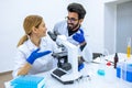 Male scientist working with microscope, doctor's team in laboratory doing research. Royalty Free Stock Photo