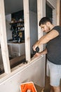 Male with a Screwdriver in his hand fixes a wooden structure for a window in his house. Repair yourself