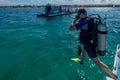 Male scuba diver with equipment jumps in water