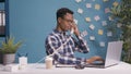 Male secretary answering landline phone at desk with laptop