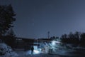 A male security guard shines a flashlight at a hydroelectric power station at night in winter Royalty Free Stock Photo