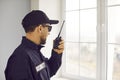 Male security guard is talking on his radio while standing by window inside house Royalty Free Stock Photo