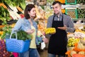 Male seller is assisting customer to buy fruit and vegetables