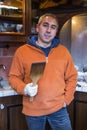 Male seller chef baker in orange sweater in kitchen