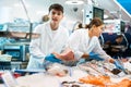 Male seller demonstrates large piece of tuna fillet at fish market Royalty Free Stock Photo