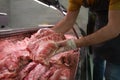 Male seller holding piece of fresh meat in butcher shop